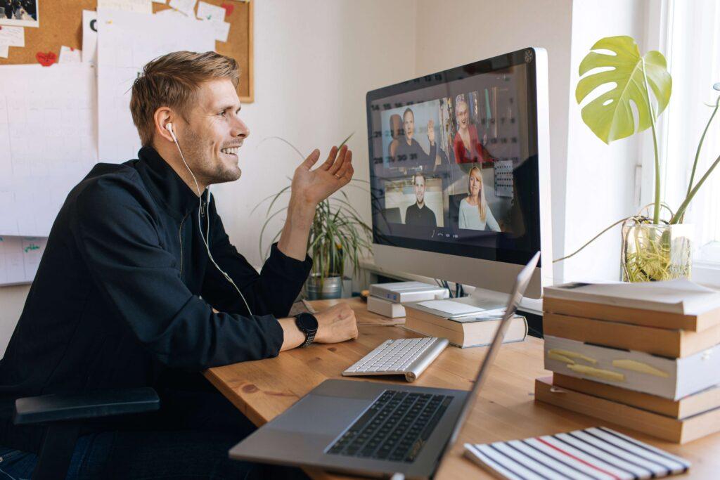 Junger Mann führt Zoom-Videoanruf über einen Computer im Heimbüro.