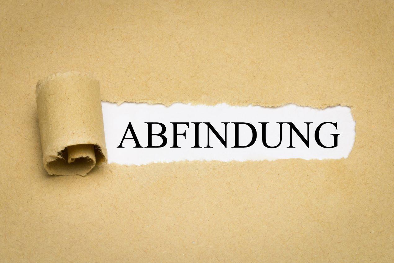 Das Wort „Abfindung“ aufgerissenes Papier – Regelungen und Höhe der Abfindungen betriebsbedingte Kündigung