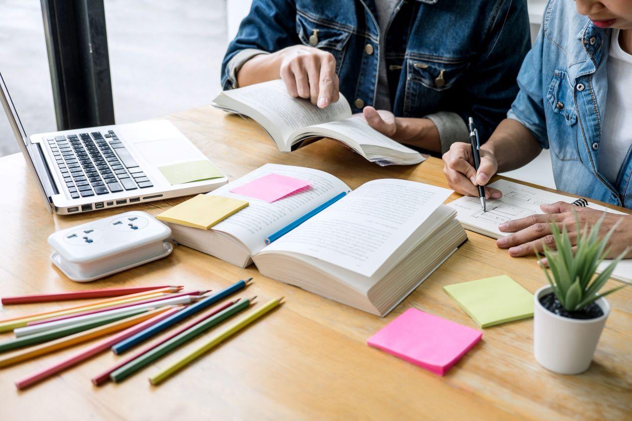 Studierende bereiten sich mit Fachbüchern und Notizen auf die Energieberater Ausbildung vor.